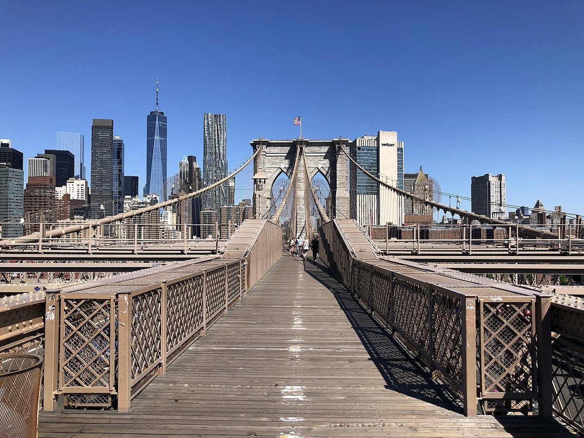 pedestrians walking across the Brooklyn Bridge in spring sunlight