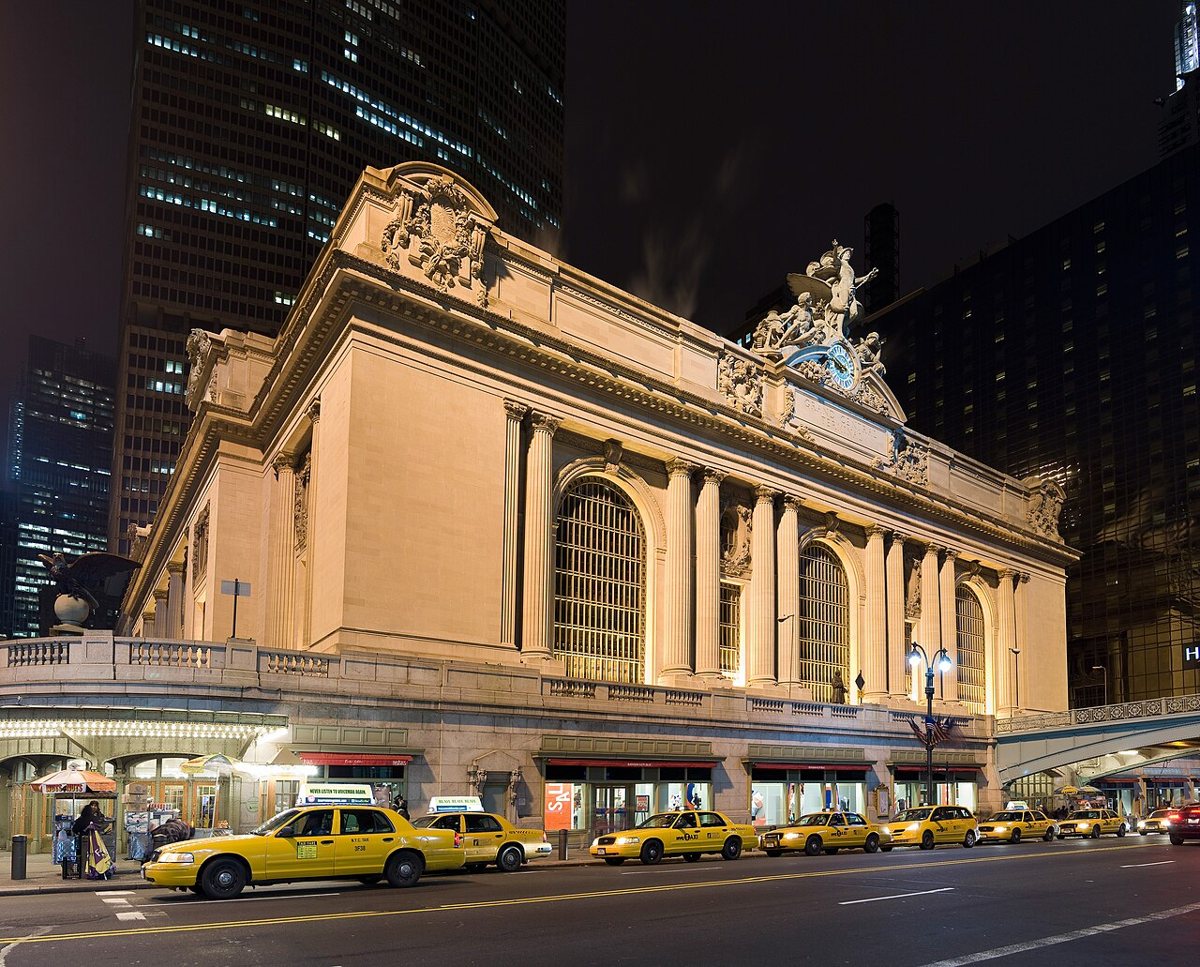 The main concourse of Grand Central Terminal with sunlight streaming through its arched windows and commuters crossing the marble floor