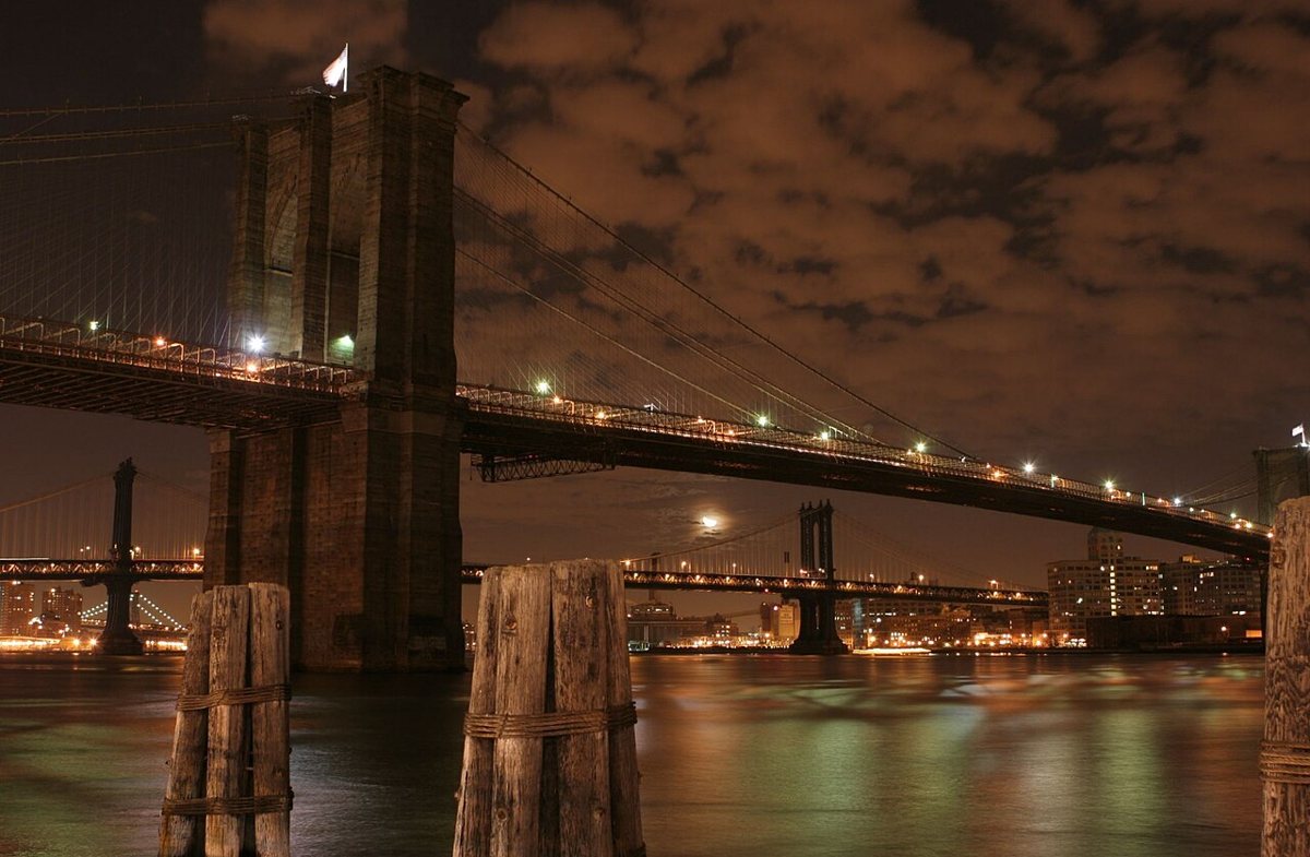 The Brooklyn Bridge's stone towers and suspension cables from the pedestrian walkway looking toward Manhattan